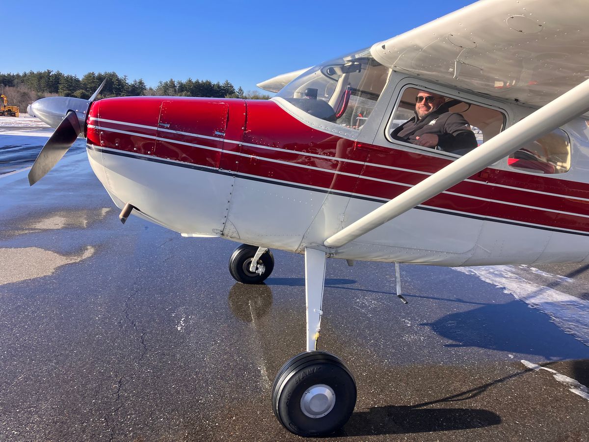 Red and white tailwheel aircraft on snowy airfield in winter